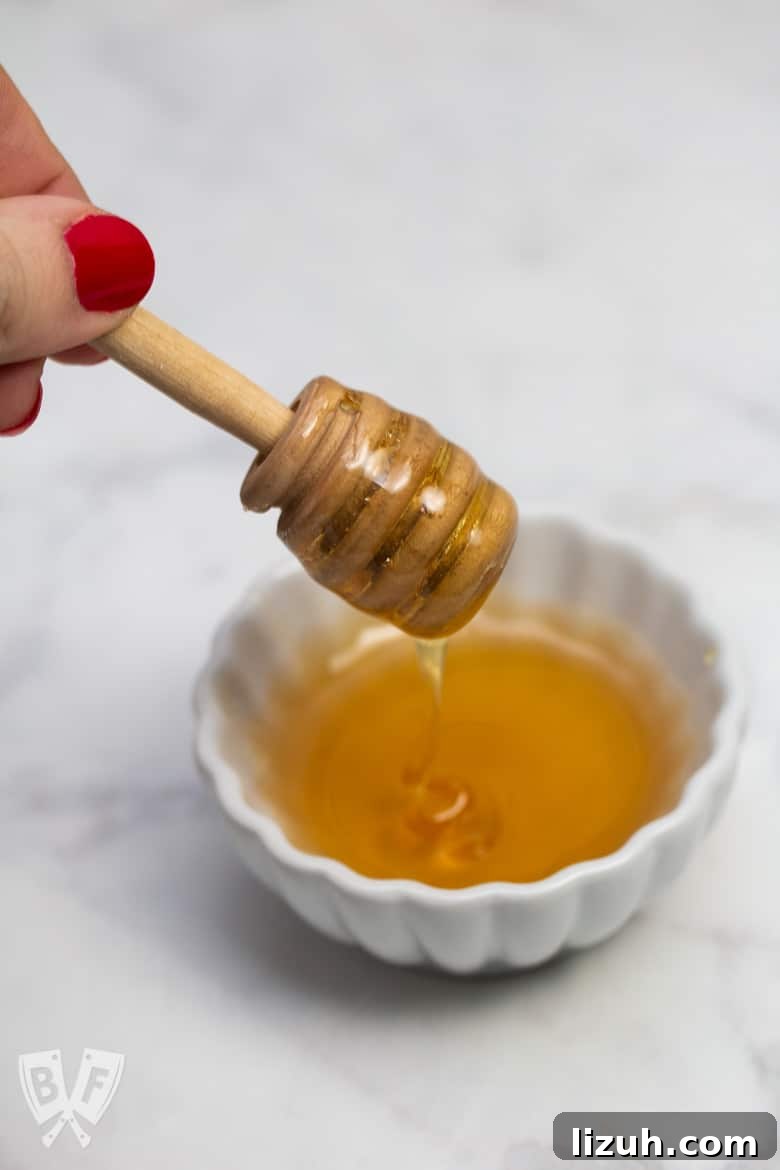 How to Make Creamy Instant Pot Yogurt at Home 15 Overhead view of a honey dipper being lifted from a bowl of honey.