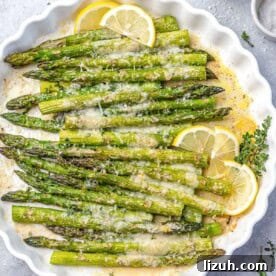 Crispy Parmesan-Roasted Asparagus — Oven-Baked Recipe 11 baked asparagus topped with parmesan cheese and lemon garnishes.