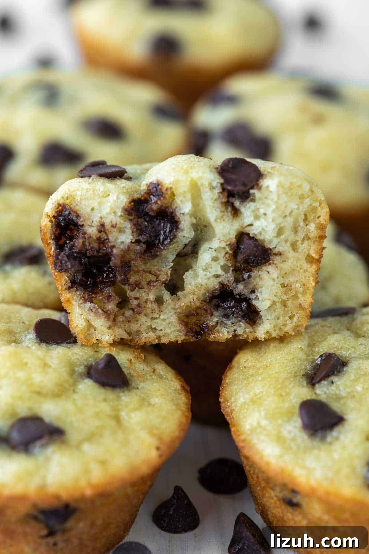 close-up of bite taken out of mini chocolate chip muffin stacked on others