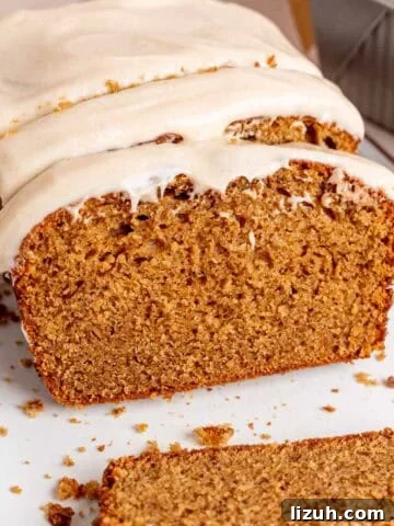 A loaf of spice cake with brown butter cream cheese frosting cut into slices.