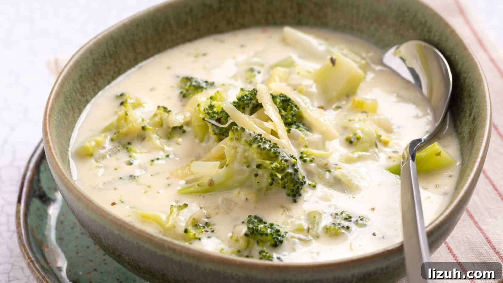 A bowl of creamy broccoli soup with chunks of broccoli, served with a spoon.