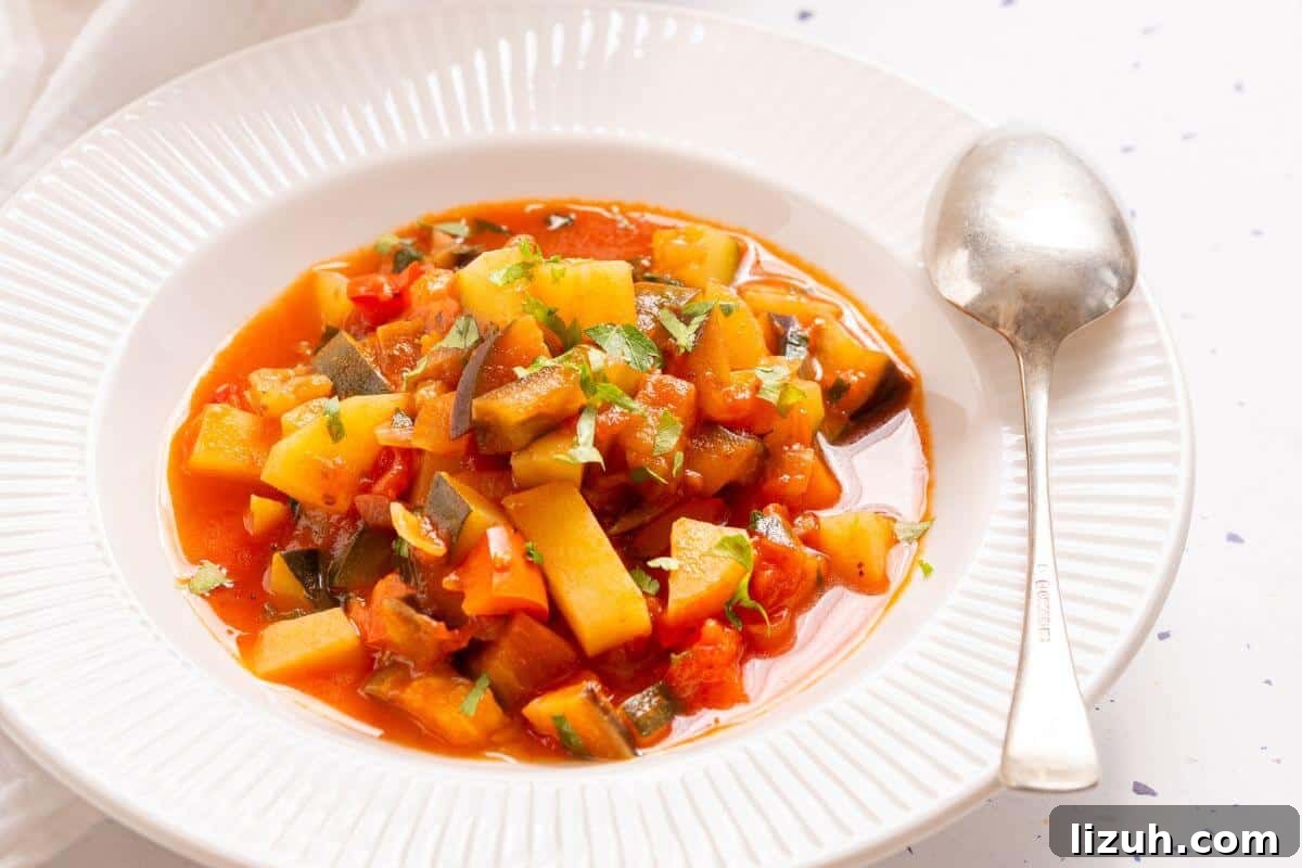 A pot of Italian vegetable stew with a spoon, garnished with chopped green herbs, on a white tablecloth with a small bowl of parsley on the side.