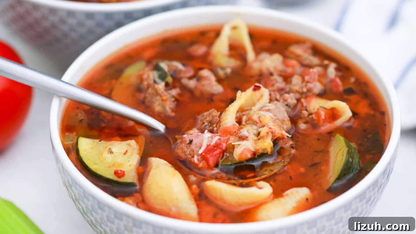 Minestrone Soup with Sausage in white bowl with spoonful.