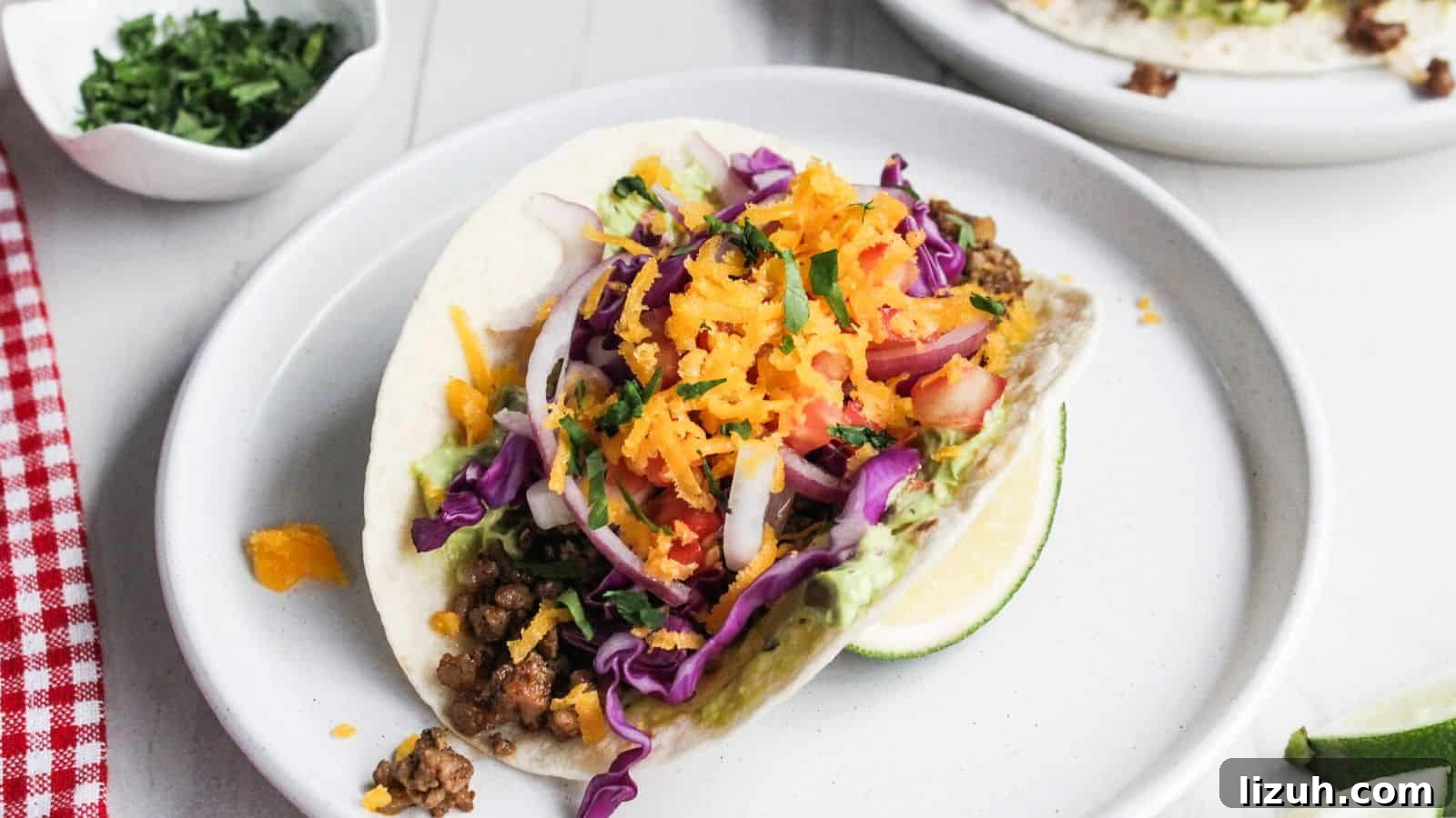 Two pork tacos on a white plate with lime wedges.