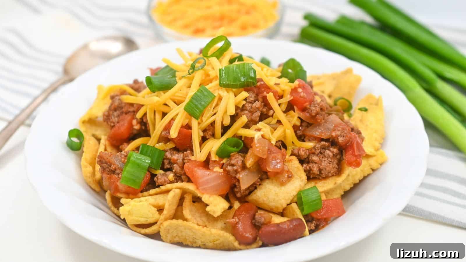 A plate of Fritos topped with ground beef, cheese, tomatoes, beans, and green onions.