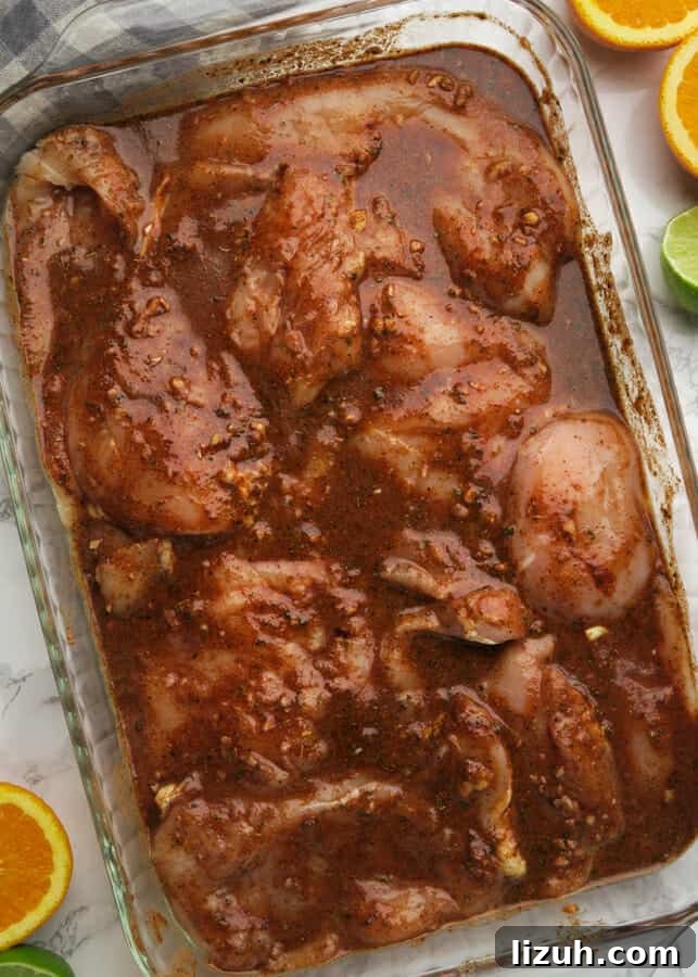 Easy Pollo Asado {Mexican Grilled or Roasted Chicken} chicken breast cutlets being marinated in achiote and citrus marinade
