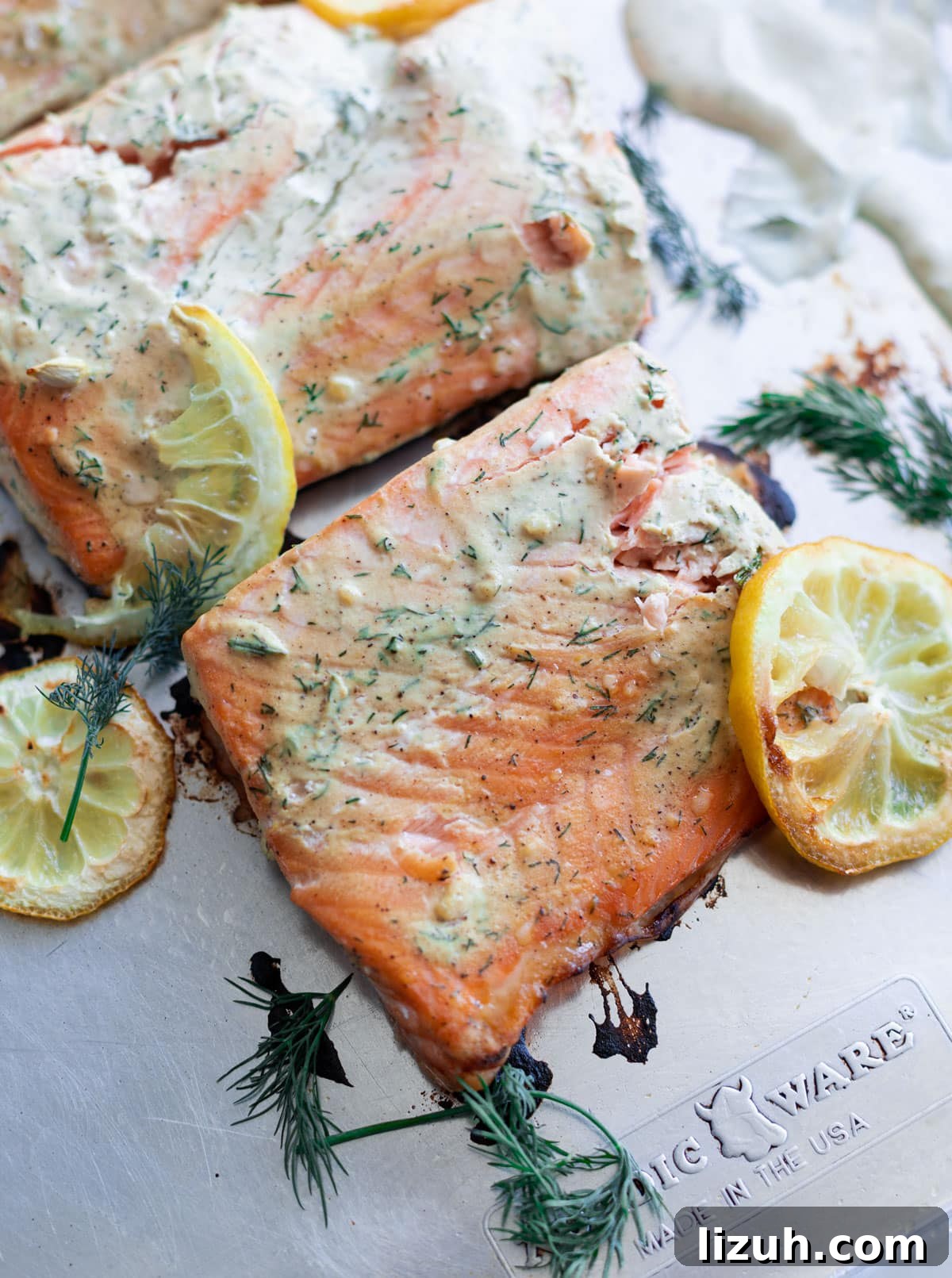baked salmon with creamy dill sauce on a sheet pan with lemon slices