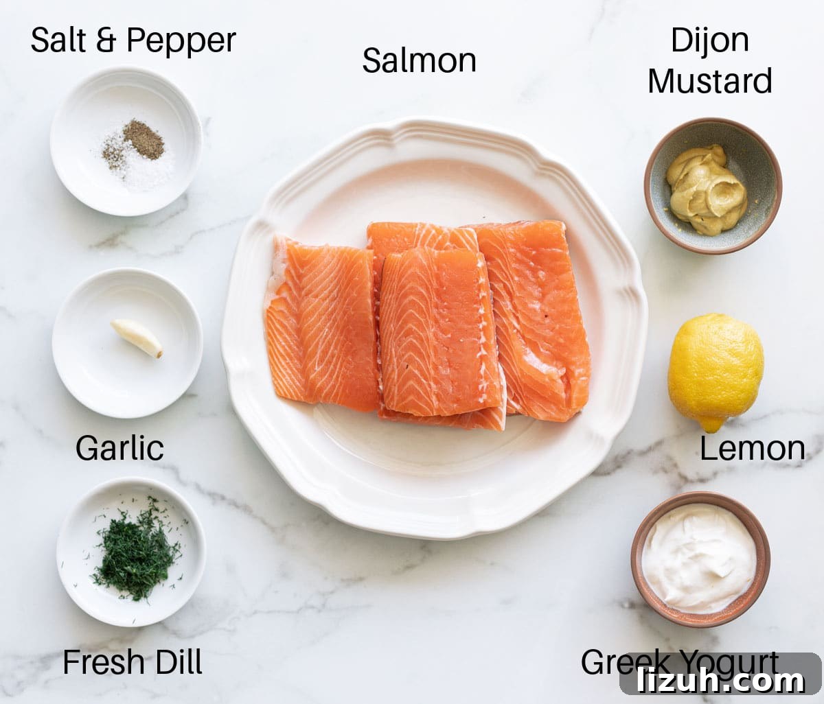 All ingredients needed to make baked salmon with dill sauce: salmon, dijon mustard, lemon, Greek yogurt, garlic, fresh dill, and salt and pepper. 
