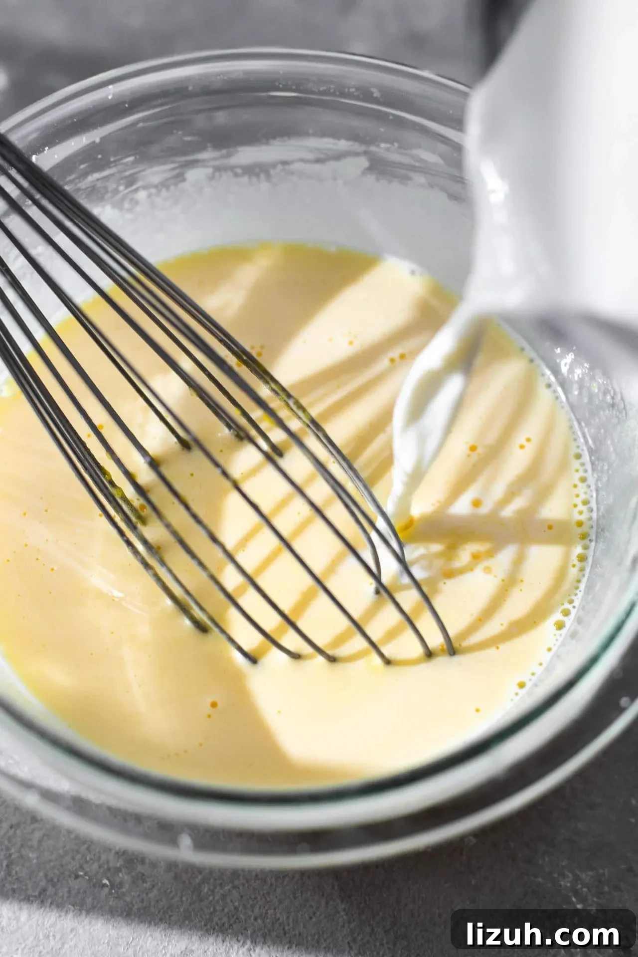 pastry cream egg mixture with milk and cream mix being slowly drizzled in to temper
