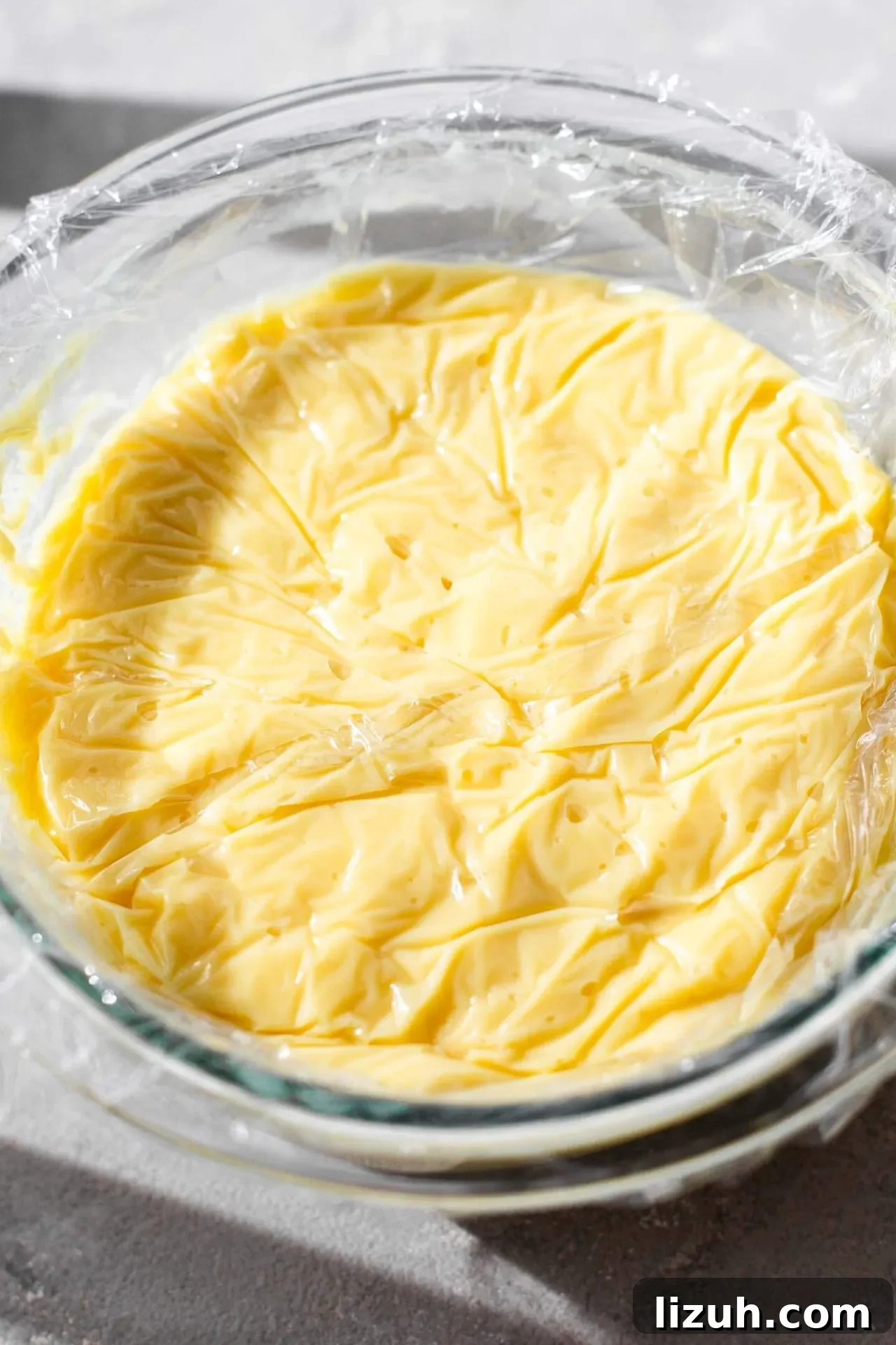 pastry cream in bowl with plastic wrap pressed against the surface