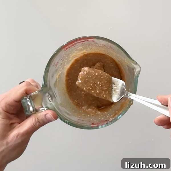 Stirring the almond butter caramel sauce with a fork in a small bowl.