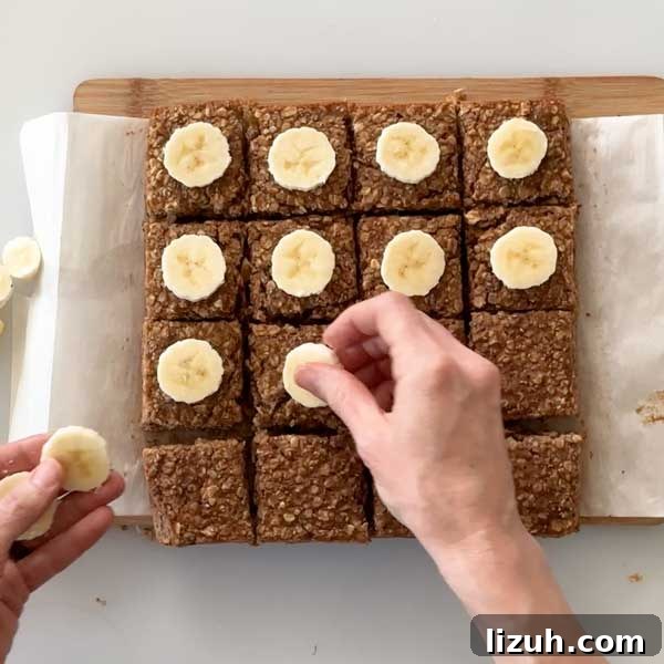 Placing sliced bananas over the sliced baked oatmeal by hand.