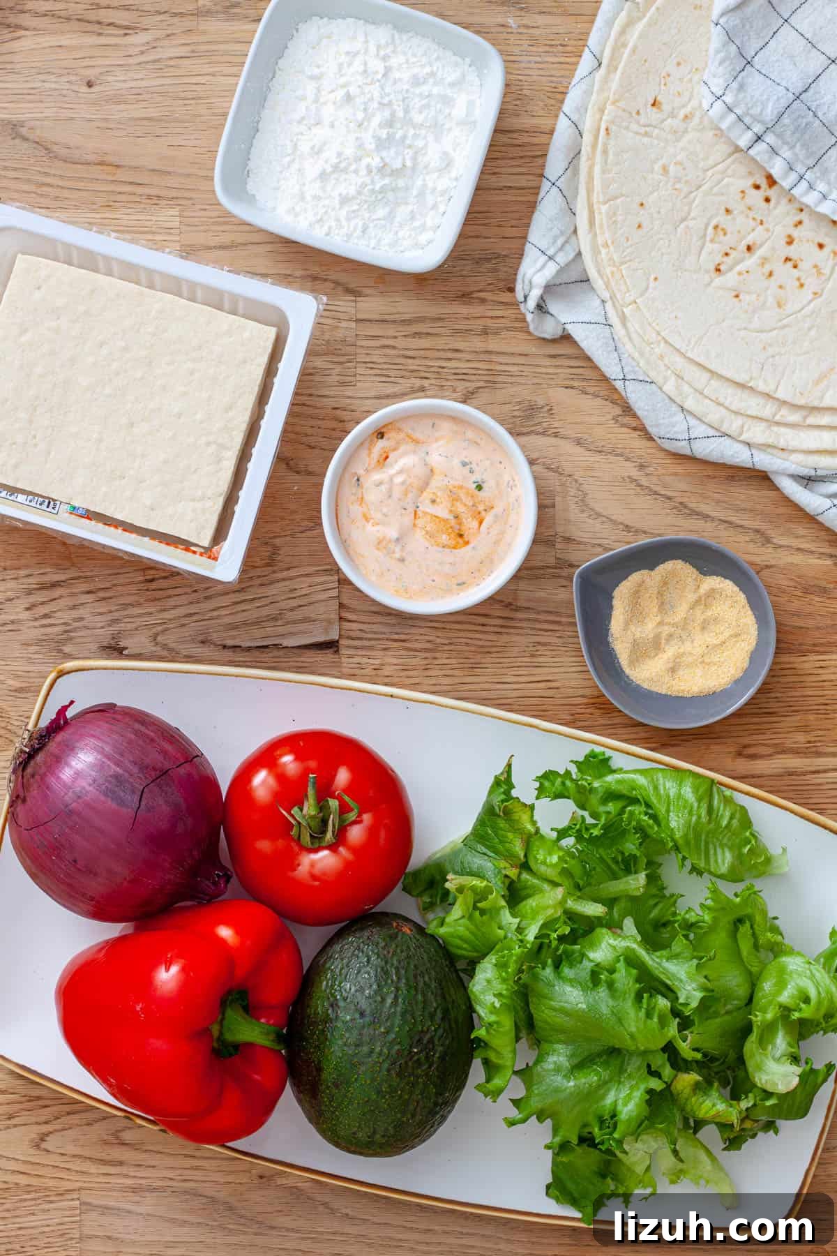 Crispy Buffalo Tofu Wraps with Cooling Ranch Slaw 3 Ingredients for crispy buffalo tofu wraps on a butcherblock cutting board.