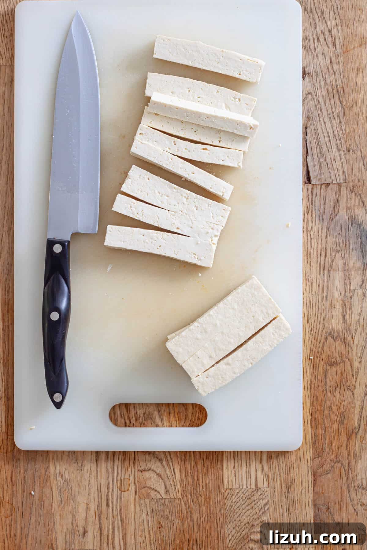 Crispy Buffalo Tofu Wraps with Cooling Ranch Slaw 4 Tofu on a cutting board getting cut into strips for tofu wraps.