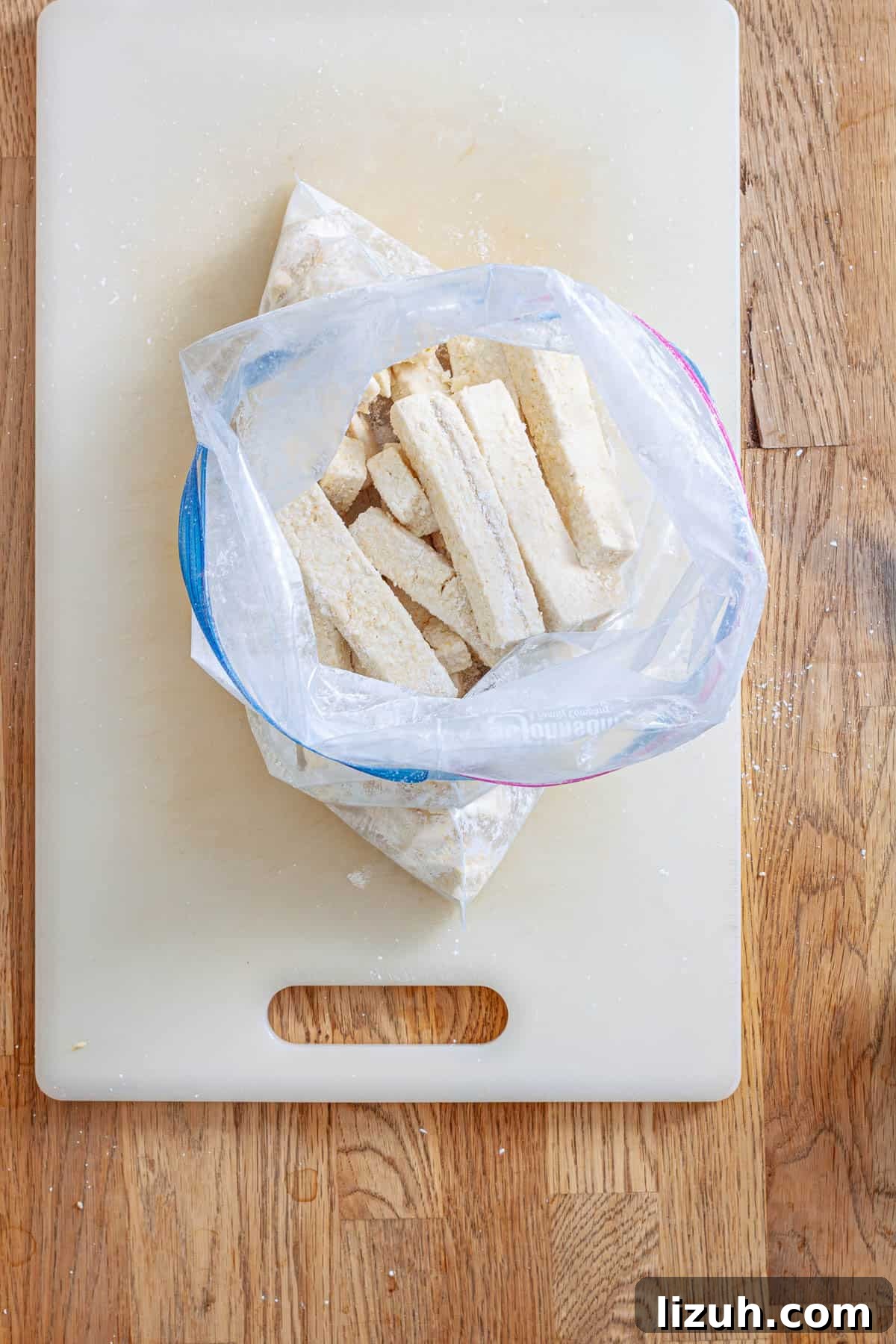 Crispy Buffalo Tofu Wraps with Cooling Ranch Slaw 5 Strips of tofu in a zip-top bag with cornstarch and seasoning getting ready to be baked.