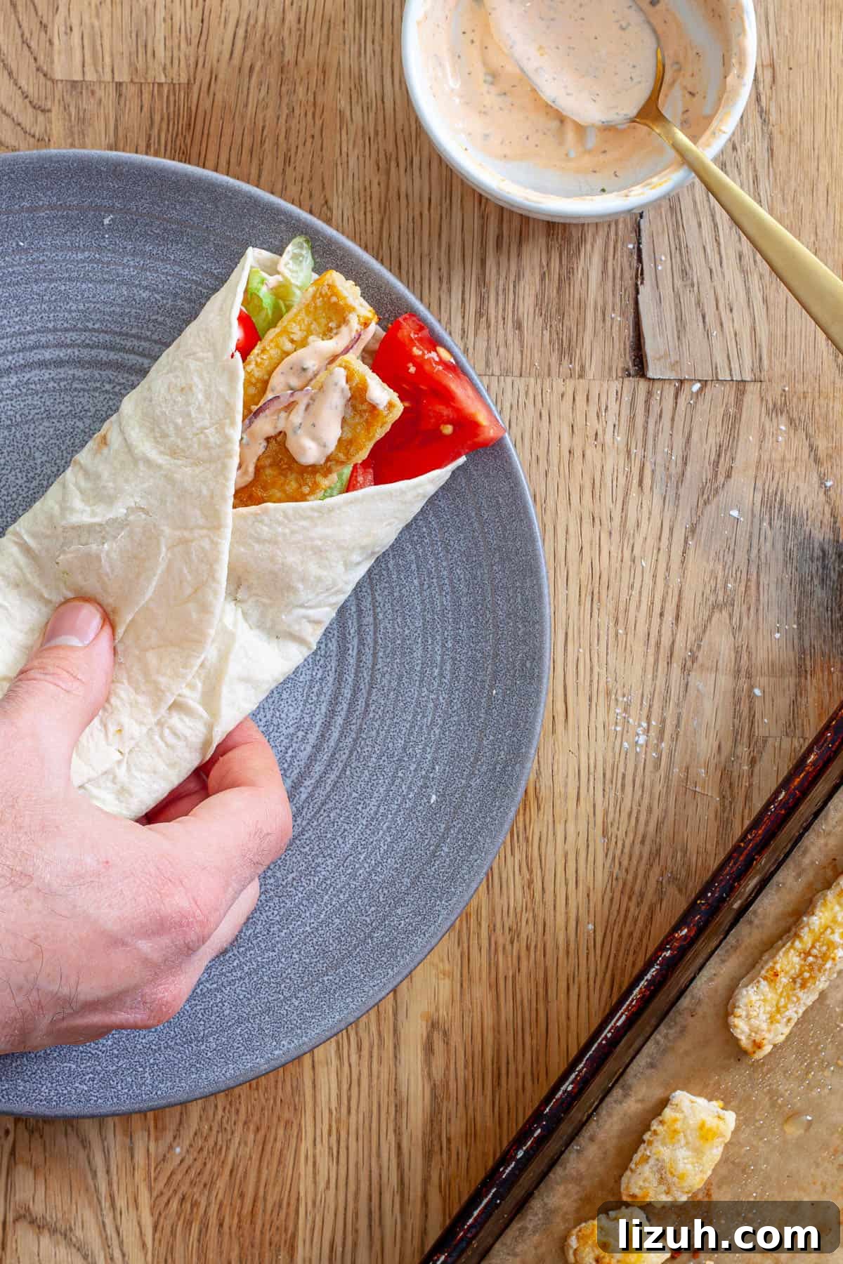 Crispy Buffalo Tofu Wraps with Cooling Ranch Slaw 9 A crispy tofu wrap on a plate getting assembled.
