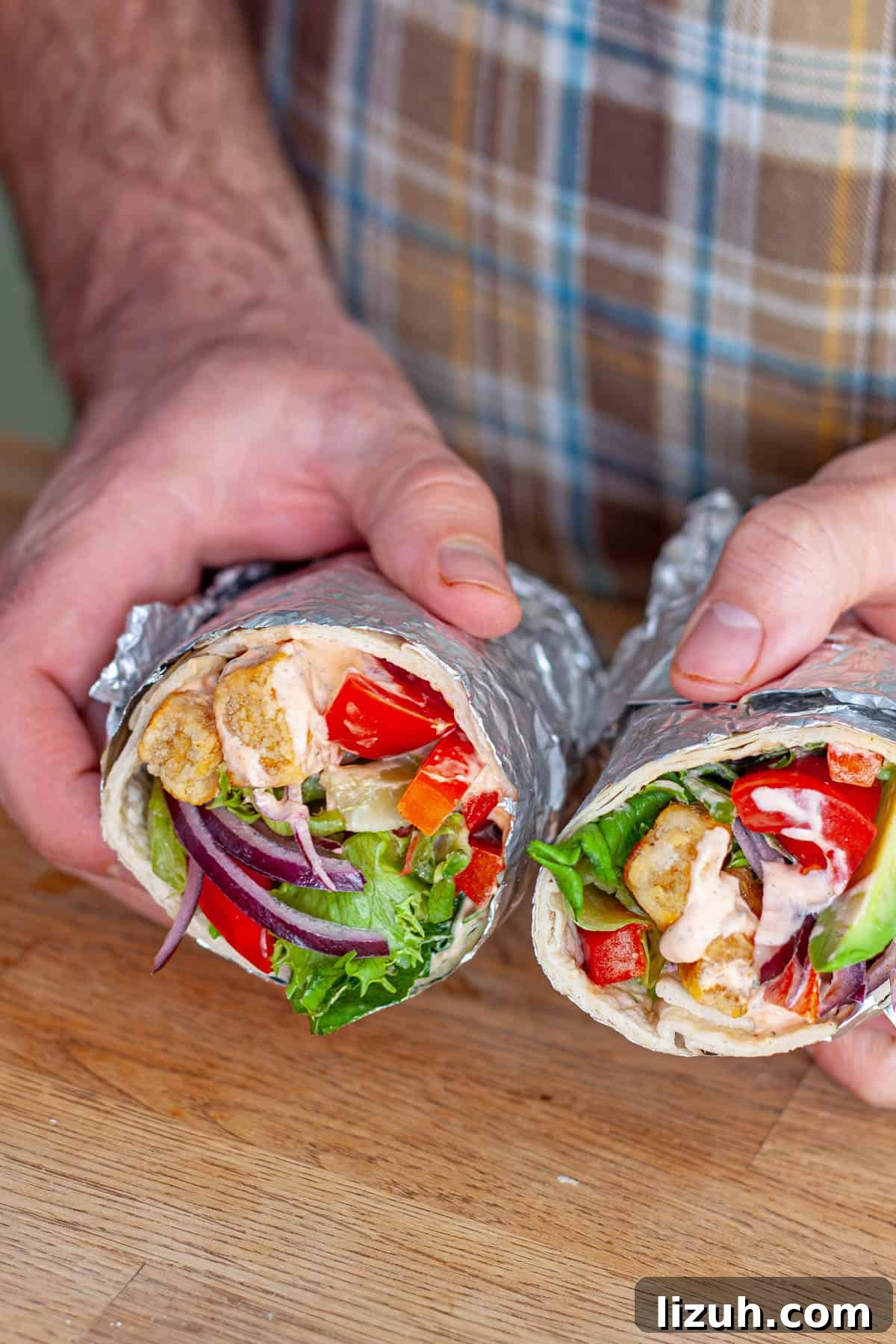 Crispy Buffalo Tofu Wraps with Cooling Ranch Slaw 10 Hands holding crispy buffo tofu wraps cut in half.