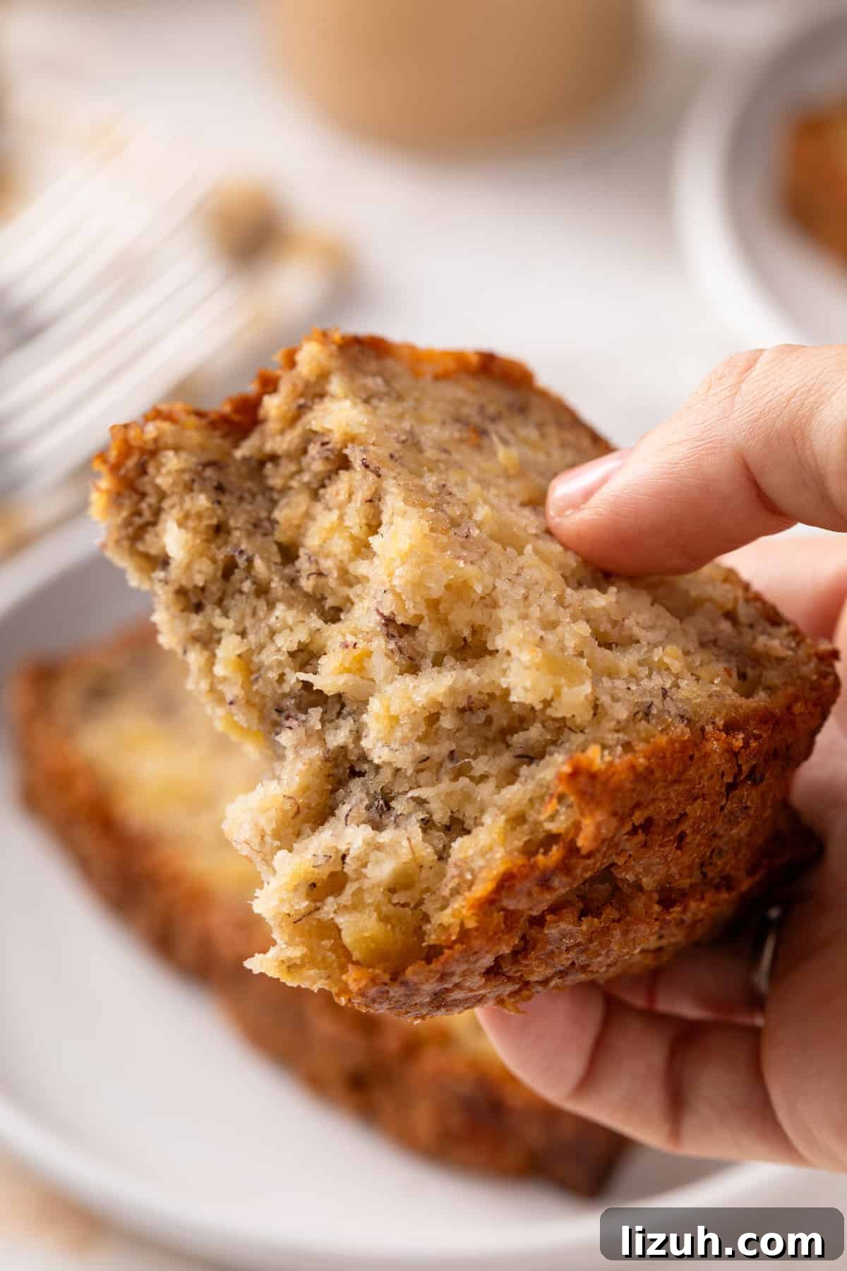 Hand holding up a slice of pineapple banana bread broken in half.