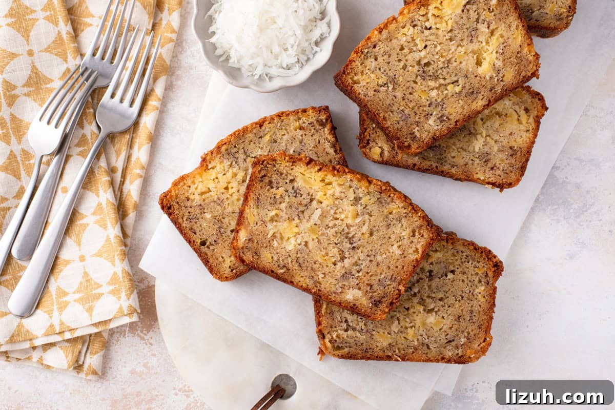 Overhead view of several slices of pineapple banana bread scattered on a piece of parchment paper.