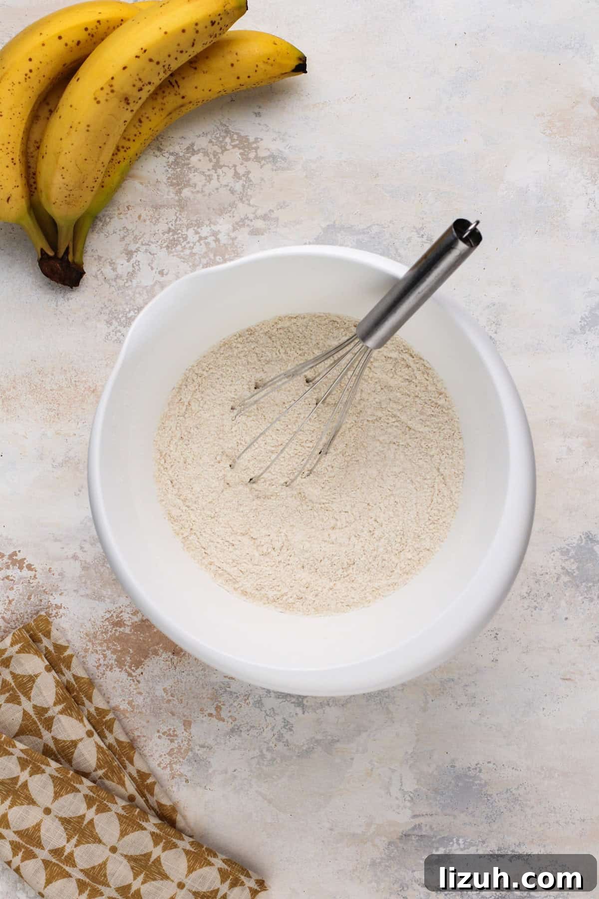 Dry ingredients for banana bread whisked together in a white bowl.