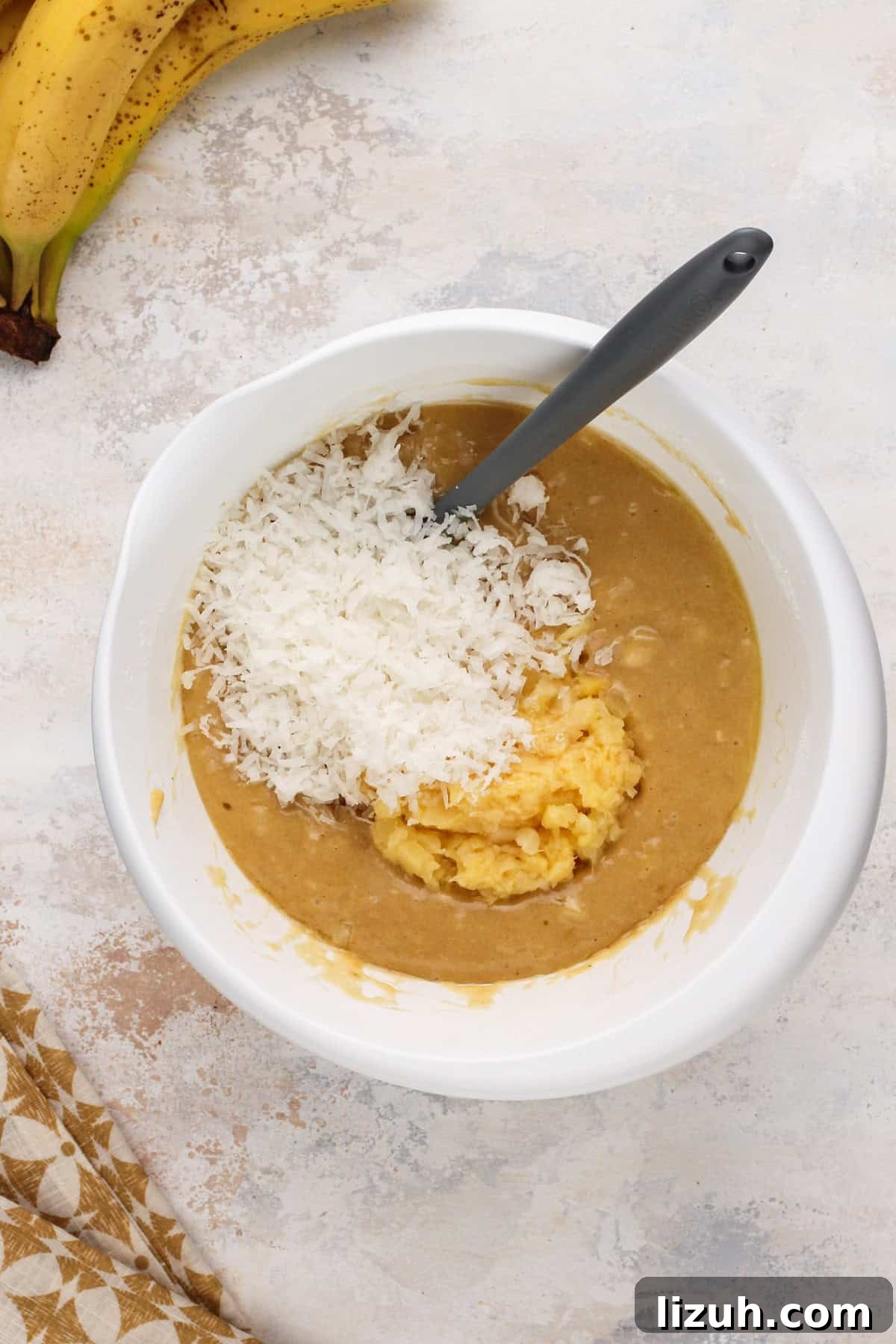 Adding crushed pineapple and shredded coconut to banana bread batter.