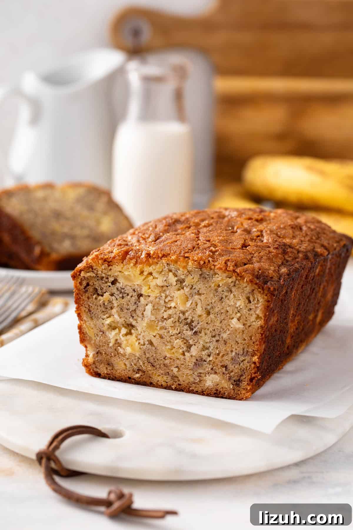 Cross section of a sliced loaf of pineapple banana bread on a piece of parchment paper.