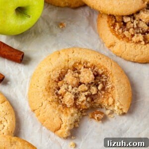 A single apple pie cookie with a bite revealing its chewy brown sugar dough and apple filling.