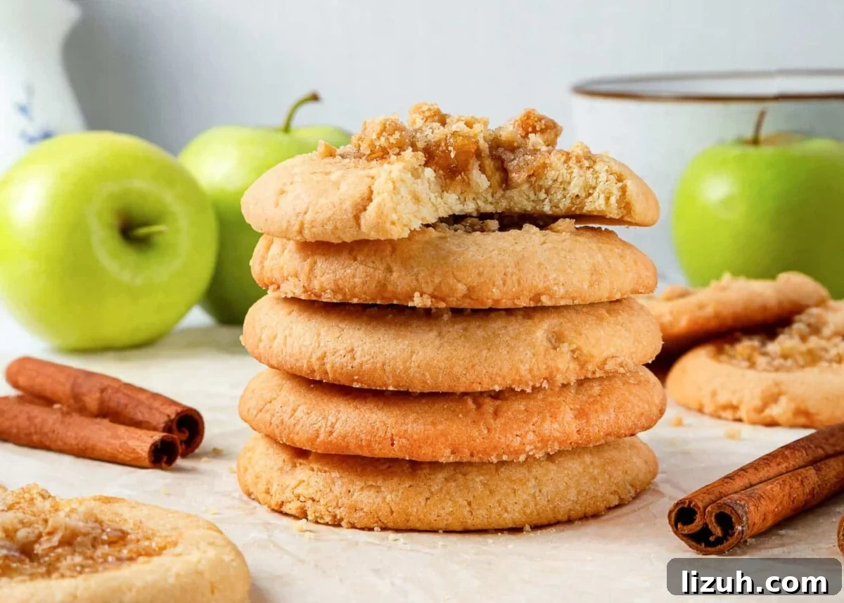 Apple Pie Cookie Recipe: Crispy Cinnamon Apple Jam Cookies 5 Baked apple pie cookies displayed beside whole green apples and cinnamon sticks for garnish.