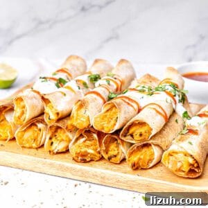 Crispy Baked Chicken Taquitos Recipe for a Flavorful Dinner 7 Two rows of piled baked chicken taquitos on a wooden board. White marbled background.