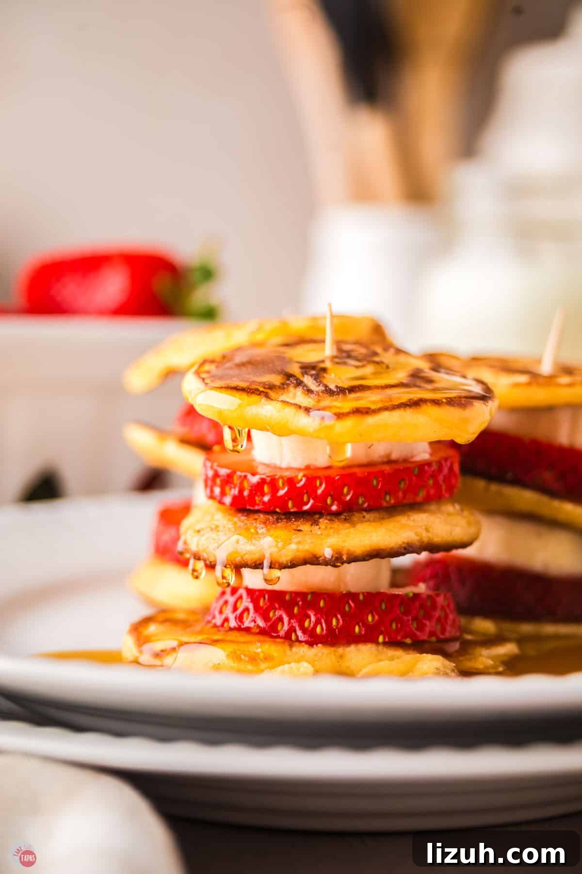 stack of mini pancakes with sliced bananas and strawberries in between them