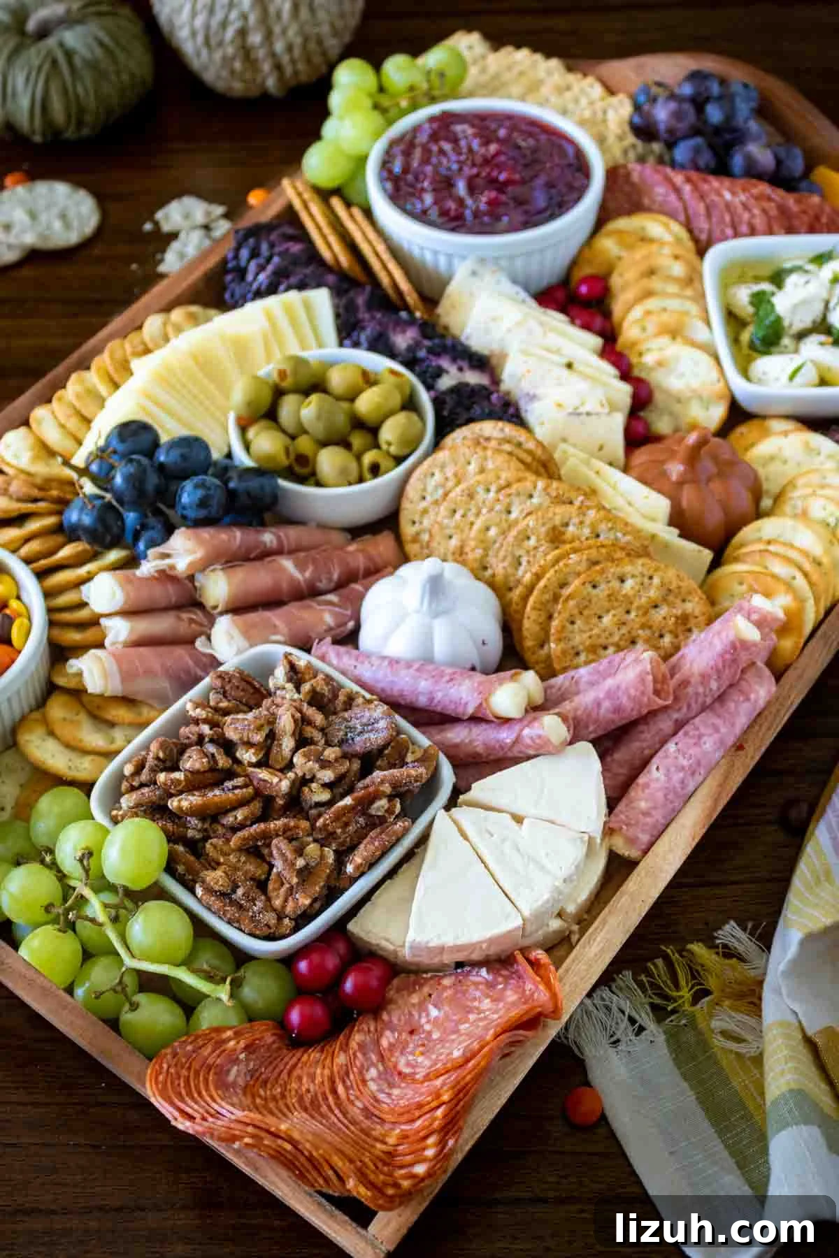 Charcuterie board with fall elements like leaves and cranberries.