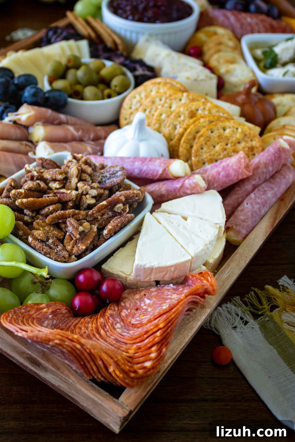 cheese, pecans, meats, and cranberries on a thanksgiving charcuterie snack board.