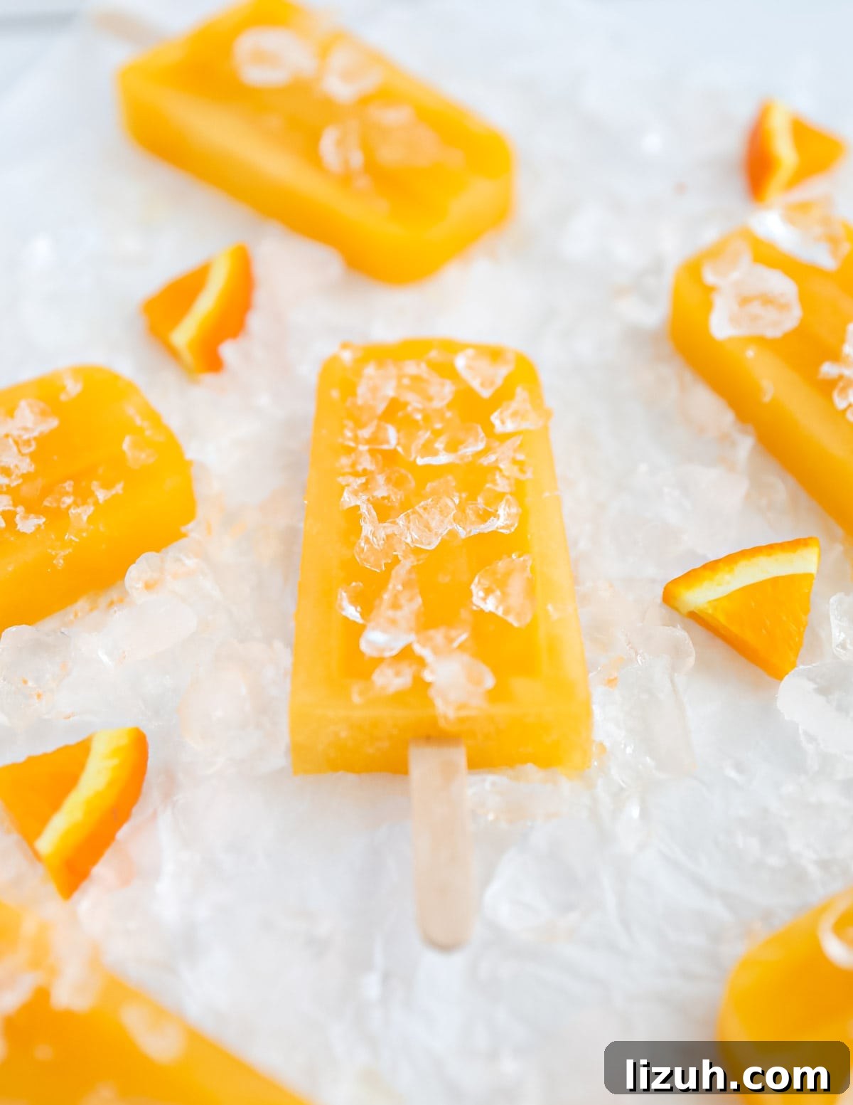 Homemade Orange Popsicles: Refreshing Citrus Ice Pops Recipe 5 Several orange ice pops resting on a bed of crushed ice