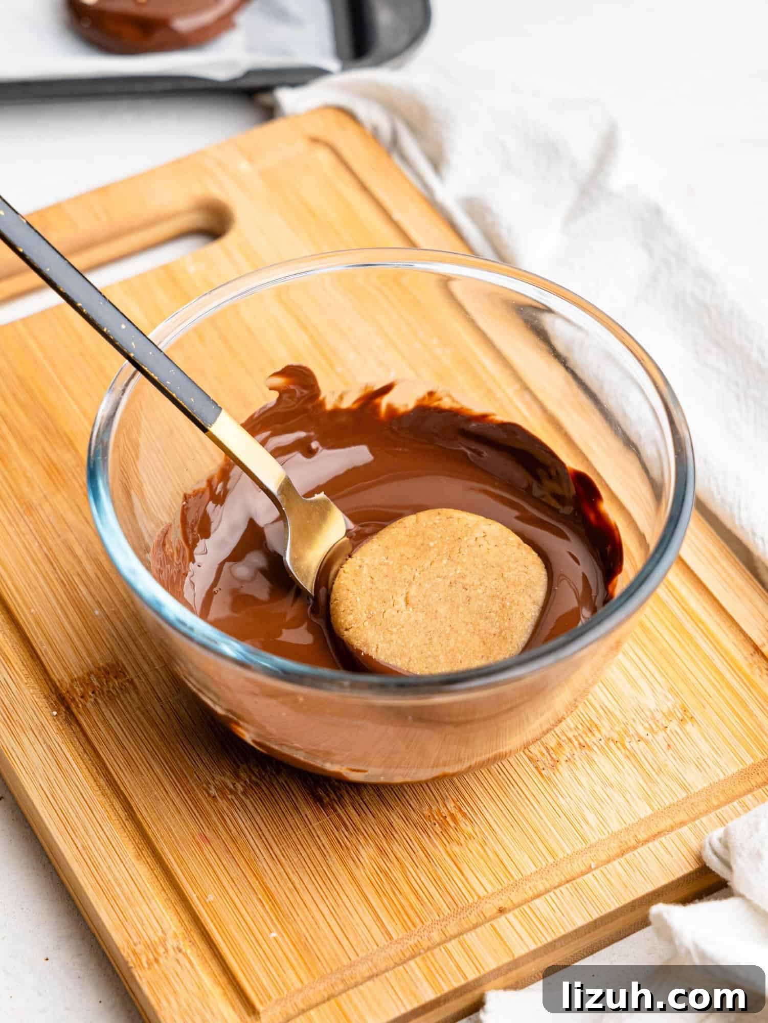 Coating a no bake pb cookie in dark chocolate.