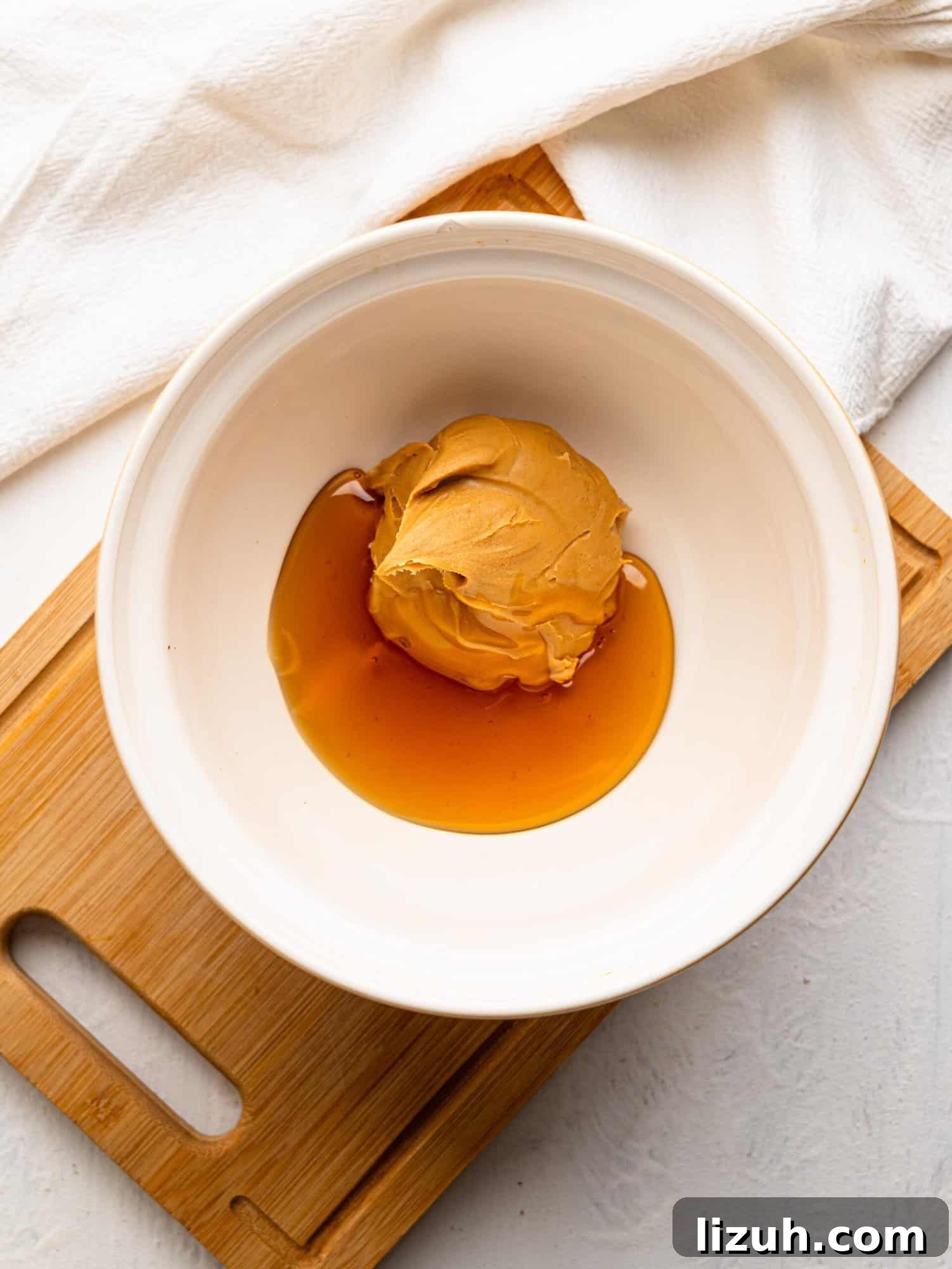 White mixing bowl with peanut butter and honey.