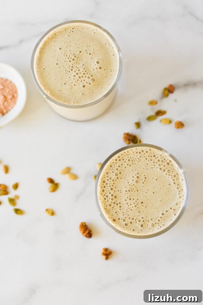An overhead shot of two smoothies next to lucuma powder, chia seeds, and mulberries