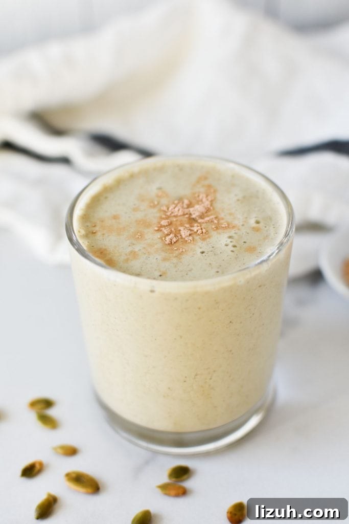 A smoothie topped with lucuma powder next to pumpkin seeds and a napkin