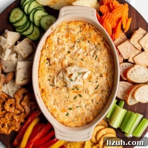 25 Perfect Pairings to Serve with Crab Dip 7 A large circular wood board with a hot crab dip in the middle with fresh produce, bread, chip and crackers around the dish.