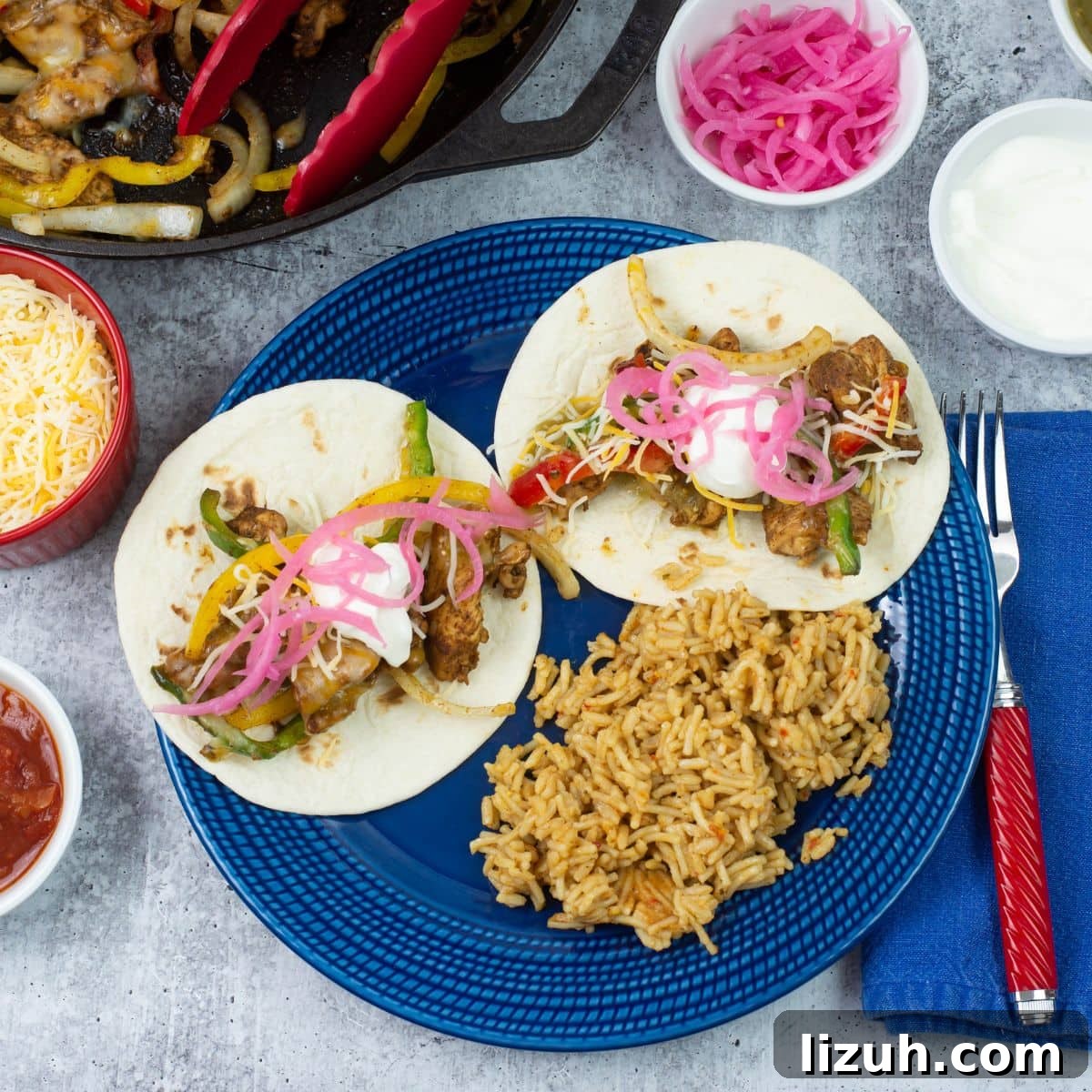 Serving fajitas with spanish rice on a blue dinner plate with toppings in background.