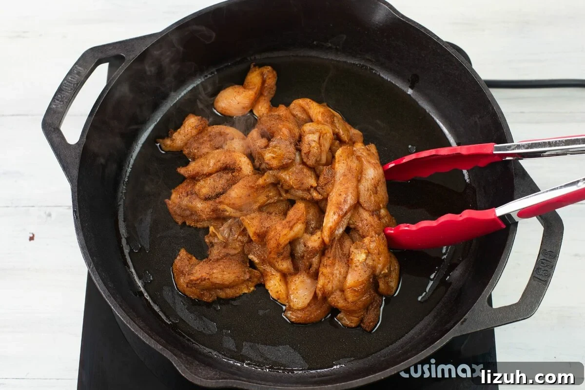 Adding chicken pieces to a hot cast iron skillet.