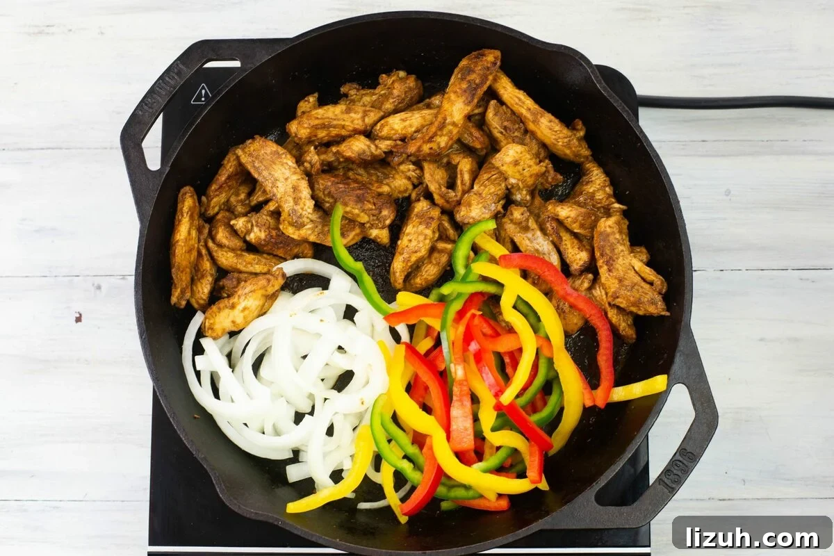 Adding sliced peppers and onions to a skillet with chicken fajita meat.