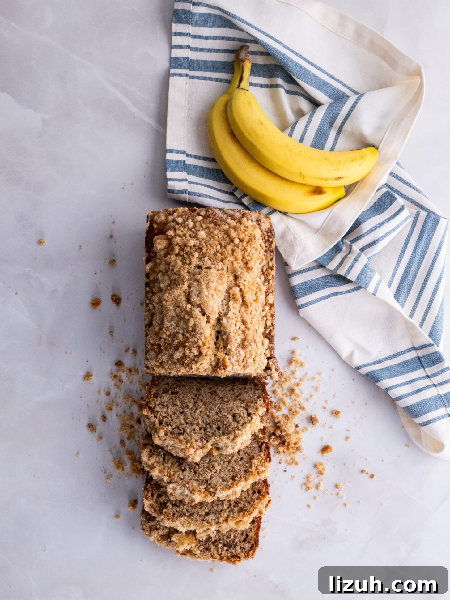 Moist Banana Bread with Crunchy Streusel Topping 2 Banana bread topped with streusel cut into slices.