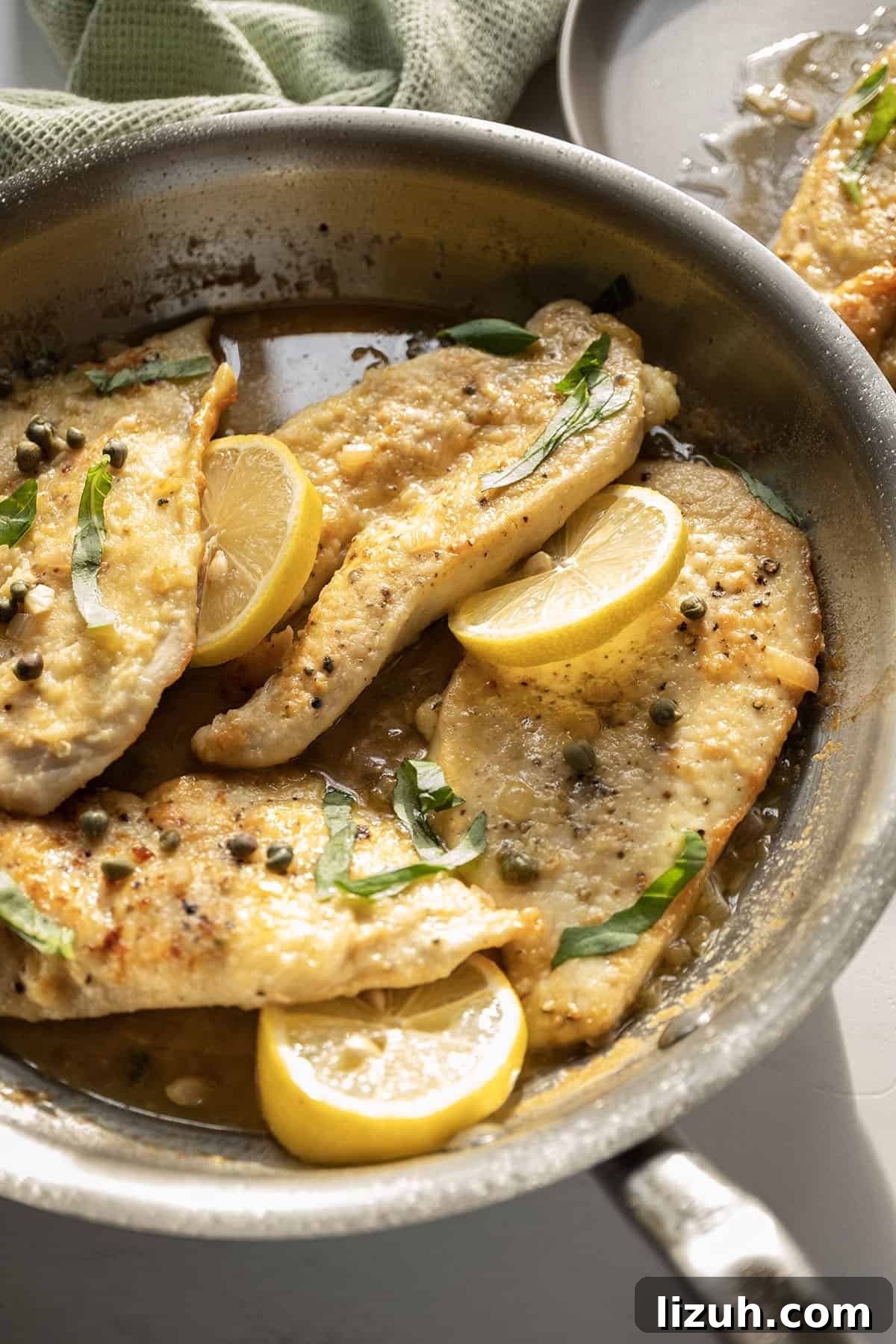 Classic Chicken Piccata Recipe: Lemon Butter Capers Guide 2 Chicken piccata in a saucepan with lemon and basil.