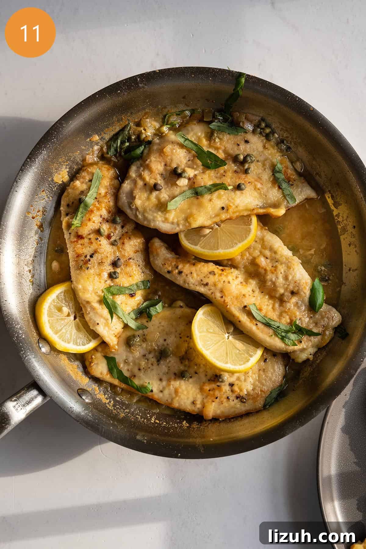 Classic Chicken Piccata Recipe: Lemon Butter Capers Guide 9 Chicken piccata in sauce pan topped with basil and capers.