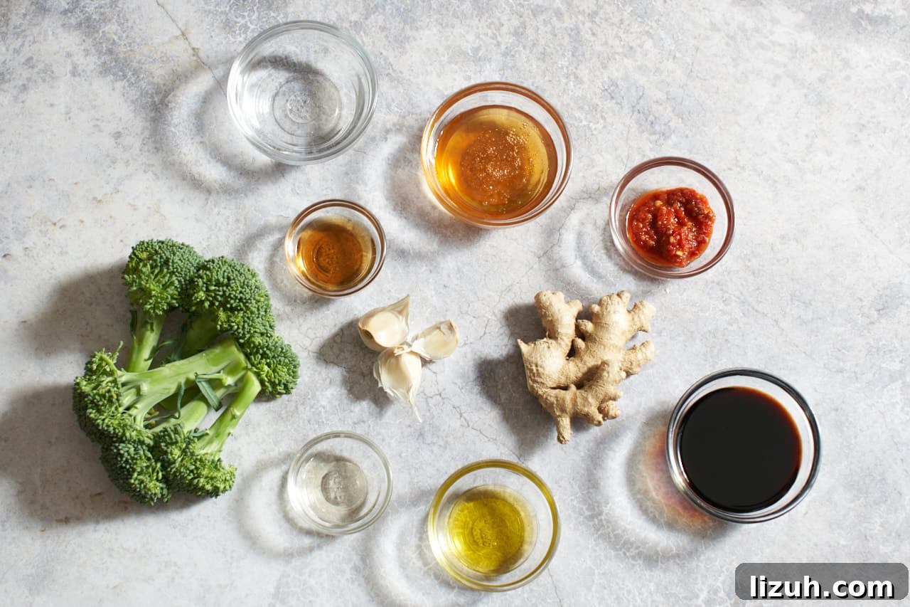 Broccoli, garlic cloves, ginger, and small bowls of rice vinegar, sesame oil, soy sauce, honey, olive oil, water, and Vietnamese chili sauce.