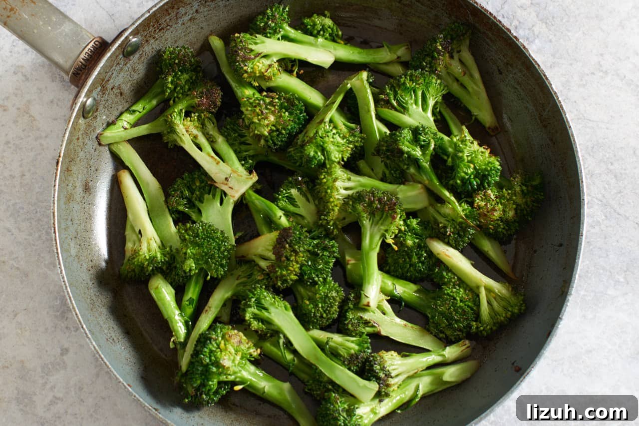 Cooked broccoli stalks with crispy edges in a skillet.