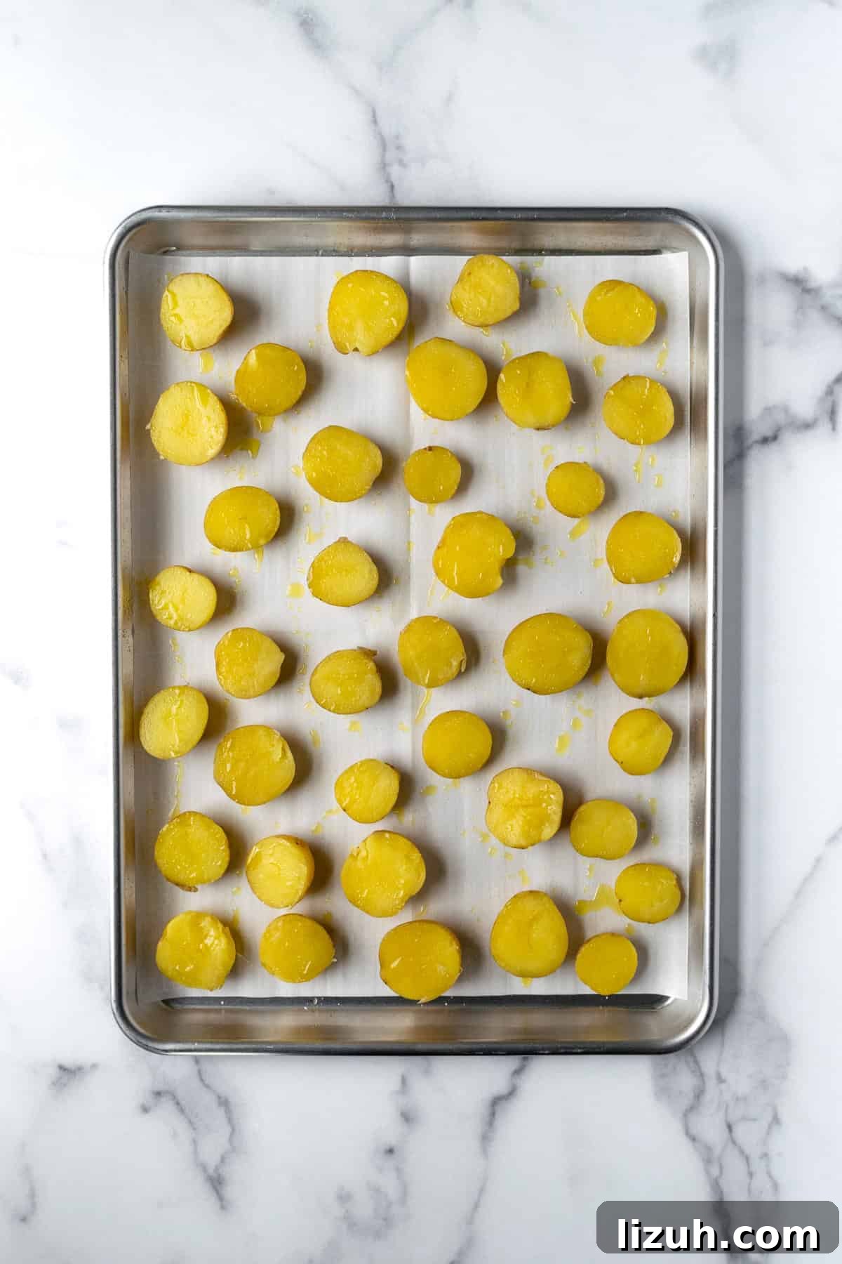 Crispy Baked Potato Bites with Garlic Herb Dip 6 Halved Mini Yellow Potatoes on a parchment lined baking sheet.