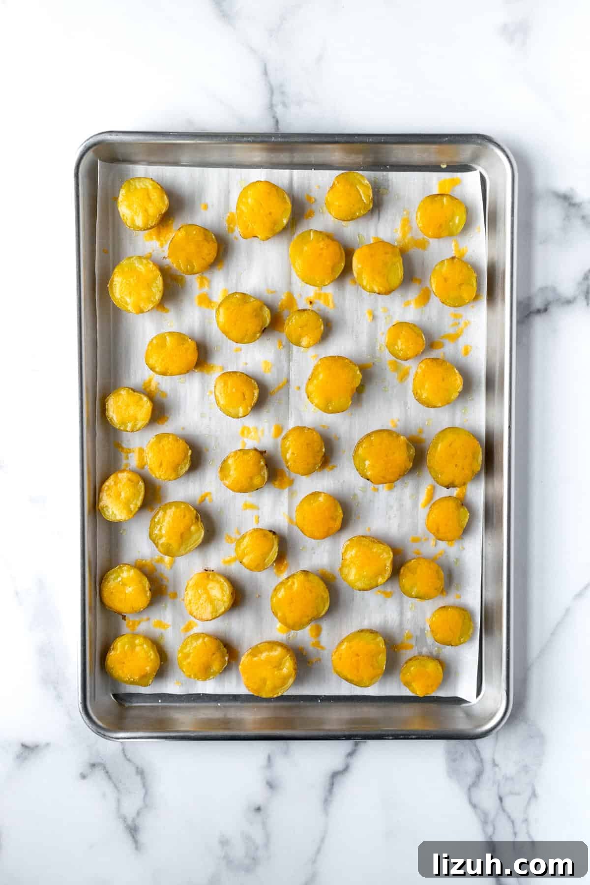 Crispy Baked Potato Bites with Garlic Herb Dip 7 Halved Mini Yellow Potatoes with Cheese on a baking sheet.