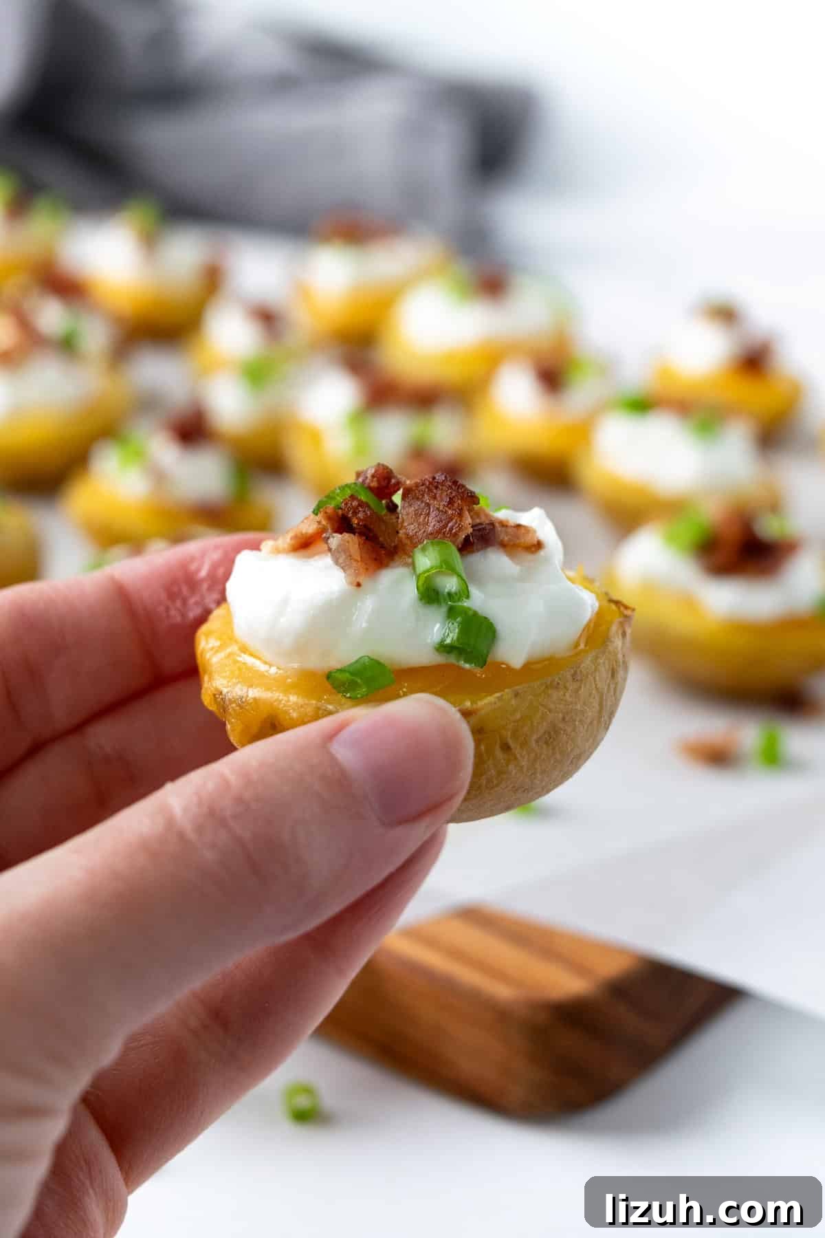 Crispy Baked Potato Bites with Garlic Herb Dip 9 A hand holding a Loaded Baked Potato Bite.