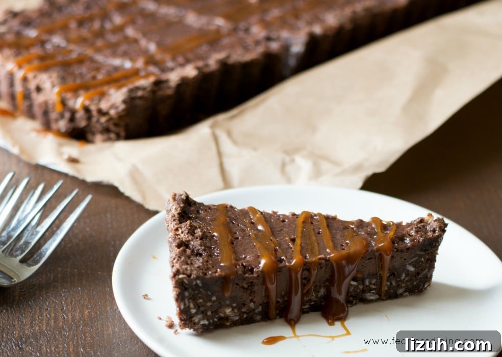 Gluten-Free Chocolate Tart with Salted Caramel Drizzle 6 A slice of Chocolate Caramel Gluten Free Tart on a white plate with the tart in the background.